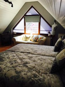 a bedroom with two beds and a couch in a attic at Gästehaus Sellemols Ferienhaus Winzer in Heuchelheim-Klingen