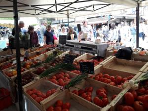 a farmers market with boxes of tomatoes and people at JOLI MAZET ST TROPEZ in Gassin