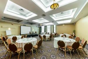 una sala de conferencias con mesas y sillas y una pantalla de proyección en Baltic Beach Hotel & SPA, en Jūrmala