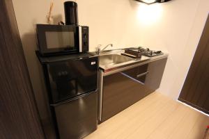 a small kitchen with a sink and a microwave at Apartment Hotel STAY THE OSAKA in Izumi-Sano