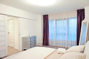 Un dormitorio con una cama y una cómoda y una ventana. en CosmopolitApart, en Sibiu 8 fotos más