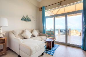 a living room with a couch and a sliding glass door at Ocean Breeze in Placencia Village +92 photos
