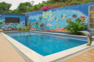 a swimming pool at a resort with a mural on the wall at Pousada Verdes Mares in Maragogi