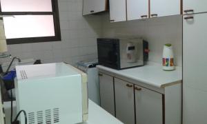 a kitchen with a microwave and a refrigerator at Residencial flat Golden beach.. in Guarujá
