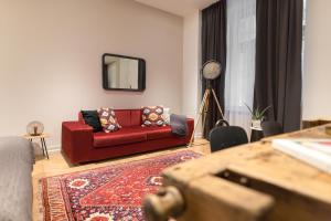 a living room with a red couch and a mirror at TG Hotel Apartments Budapest in Budapest