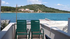 2 krzesła na balkonie z widokiem na plażę w obiekcie Volat Apartments w mieście Betina