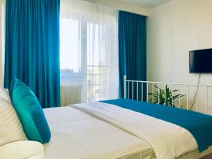 1 dormitorio con 1 cama con cortinas azules y ventana en Pipera Lake View Bright Apartament, en Bucarest