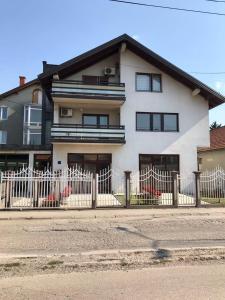 ein weißes Haus mit einem Zaun davor in der Unterkunft Apartments Dreams Centar in Živinice