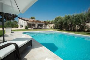 a swimming pool with an umbrella and a house at Villa mare Fontane Bianche in Fontane Bianche