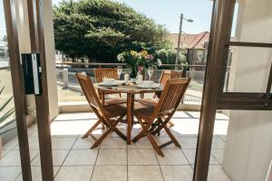 een houten tafel en stoelen op een balkon bij 2-Bedroom Apartment within 1km of The Point Beach in Mosselbaai