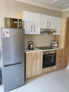 a kitchen with white cabinets and a stainless steel refrigerator at Melville Mews-2- Auckland park in Johannesburg