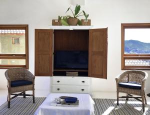 uma sala de estar com televisão e duas cadeiras em CASA PIÚVA em Ilhabela