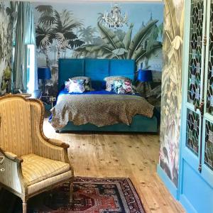 1 dormitorio con 1 cama azul y 1 silla en La Rebière d'Or, B&B et Gîte en Mouleydier