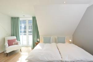 a bedroom with a white bed and a white chair at Luk Hüs in Westerland