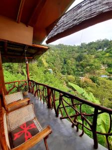 a balcony with chairs and a view of a forest at NatureWoodland in Ella