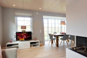 ein Wohnzimmer mit einem TV und einem Tisch mit Stühlen in der Unterkunft Luk Hüs in Westerland
