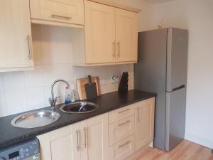 a kitchen with a sink and a refrigerator at Telford Road Apartment in Inverness