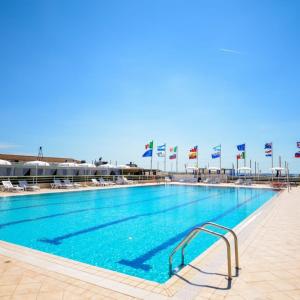 a large swimming pool with flags in the background at Residence Lagomare dal Barza in Torre del Lago Puccini