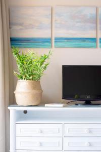 a white dresser with a tv and a plant on it at Apartamentos Punta Marina by LIVVO in Morro del Jable