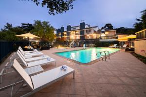 einen Pool mit Liegestühlen neben einem Gebäude in der Unterkunft Mariposa Inn and Suites in Monterey