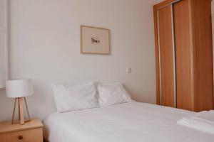 a bedroom with a white bed and a wooden door at T1 central e calmo, moderno e acolhedor em Coimbra - Self check in in Coimbra