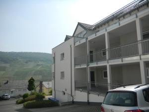 a white building with a car parked in front of it at Ferienwohnung Bernkastel-Kues - Alte Rebschule in Bernkastel-Kues