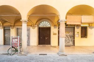 un vélo garé devant un immeuble avec piliers dans l'établissement Residenza Ariosto by Studio Vita, à Bologne
