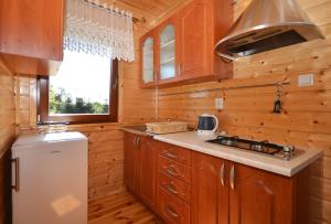 a kitchen with wooden cabinets and a refrigerator at Domki Alicja in Darłowo