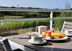 a table with breakfast foods and coffee on a balcony at Westotel Life Appart'hotels Pornic - Résidence 4 etoiles in Pornic