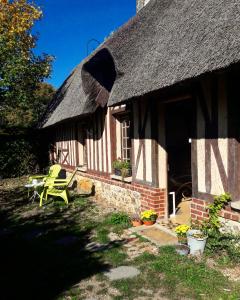 a house with a thatched roof and a green chair at La chaumière des deux amants in Vatteville