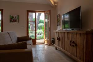 a living room with a flat screen tv on a wooden cabinet at Les Pins de l'Escalet in Ramatuelle