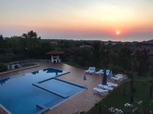 ein Pool mit Stühlen und ein Sonnenuntergang im Hintergrund in der Unterkunft Villa Anna in Leptokaryá