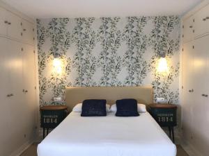 a bedroom with a white bed with two blue pillows at Hotel Nómadas in Vejer de la Frontera