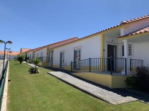 une rangée de maisons blanches et jaunes avec une cour dans l'établissement Santa Barbara Healthcare & Villas, à Mariquiteira
