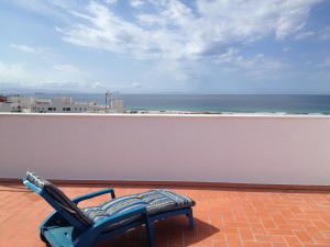 une chaise bleue assise sur un balcon avec vue sur l'océan dans l'établissement Apartamentos Ortega, à Tarifa