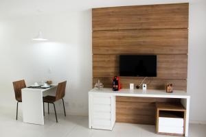 a white desk with a tv on a wooden wall at Brasilia Boutique Flats in Brasília
