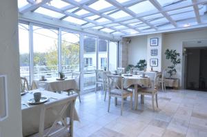 a restaurant with white tables and chairs and windows at LE SOLEIL D'OR in Joinville