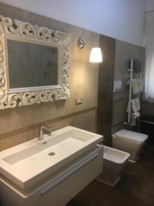 bagno con lavandino, servizi igienici e specchio di La Casa di Chris a Messina