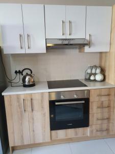 La cuisine est équipée de placards blancs et d'un four avec plaques de cuisson. dans l'établissement Melville Mews-2- Auckland park, à Johannesbourg