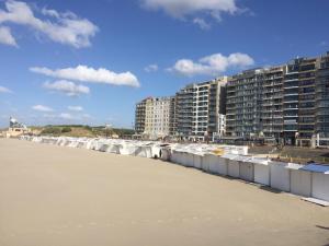 a row of buildings on the beach next to the water at Isola Bella Blankenberge in Blankenberge