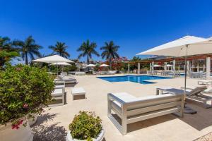 una piscina con sillas y sombrillas junto a un complejo en Magia Beachside Condo, en Playa del Carmen