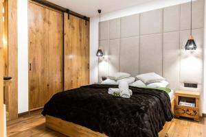 a bedroom with a large bed with black blanket and white pillows at Nowy komfortowy Apartament & Spa Grizzly de lux in Zakopane