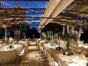 un salón de banquetes con mesas blancas, sillas y luces en Masseria Li Reni, en Manduria