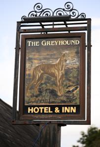 una señal para un hotel y una posada con una foto de un perro en The Greyhound Inn and Hotel, en Usk