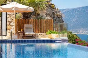 a swimming pool with an umbrella and a table and a chair at Villa Yar in Kalkan