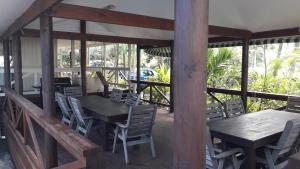 a dining room with wooden tables and chairs on a deck at Te Akapuao Studio Villas in Rarotonga