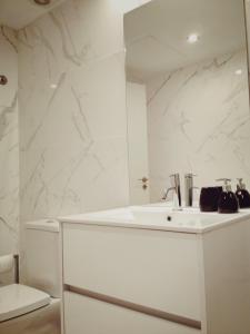 een witte badkamer met een wastafel en een spiegel bij Boavista Garden Apartment in Porto +20 foto's