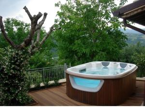 a hot tub sitting on a deck next to a tree at Casa delle Noci b&b in Rosora