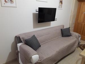 salon z kanapą i telewizorem na ścianie w obiekcie Rosa Holiday Home w Syrakuzach