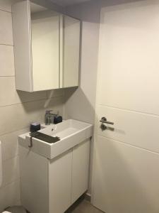 a white bathroom with a sink and a door at Studio apartman Park Galerija in Osijek